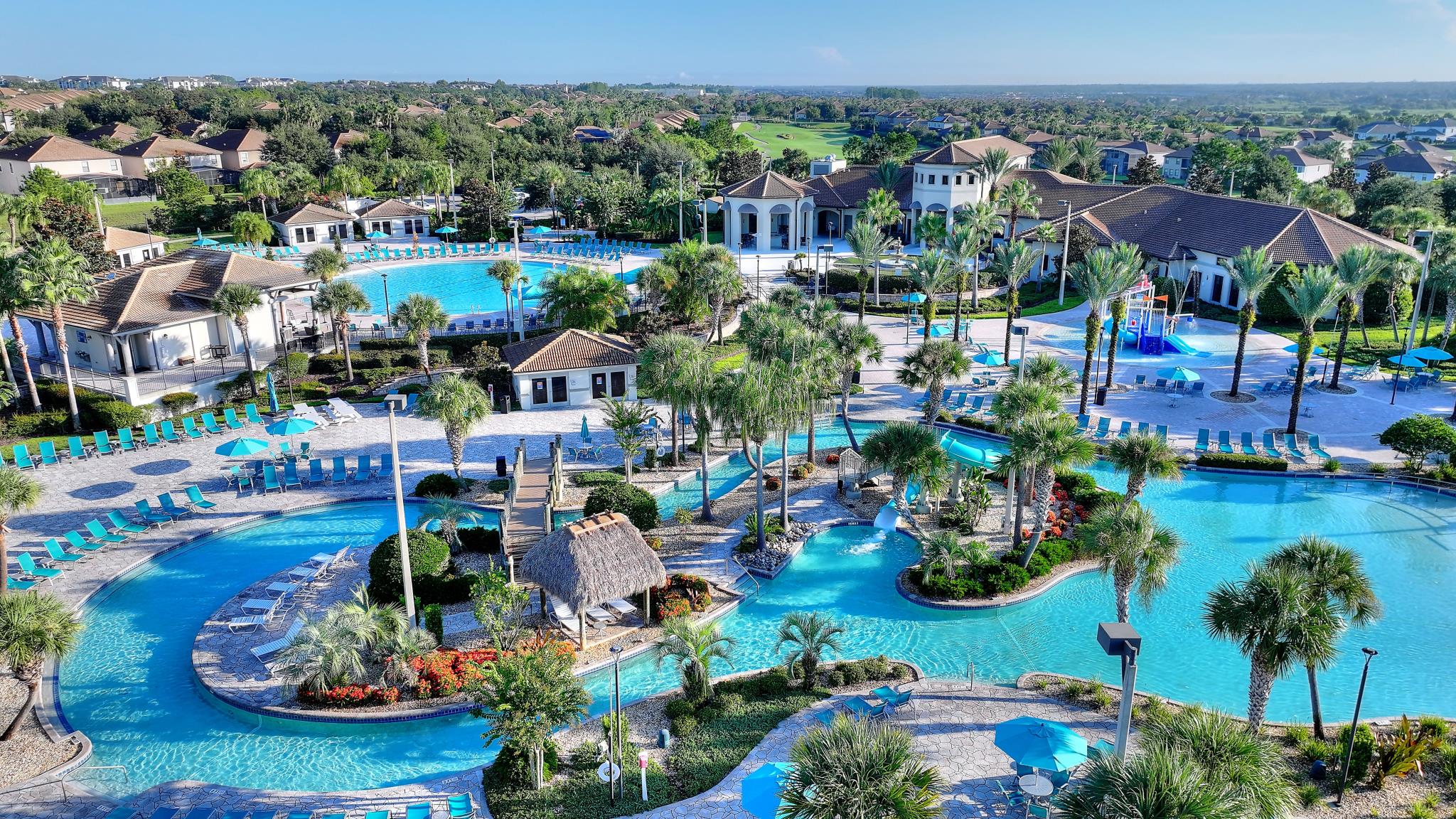 A sparkling resort pool lined with palm trees and sun loungers at the Oasis Club in ChampionsGate